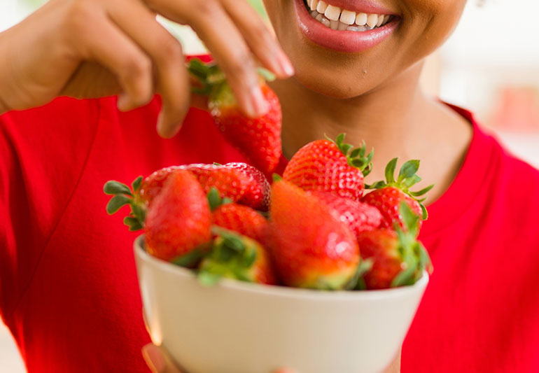 A woman smiling with a bowl filled with strawberries
